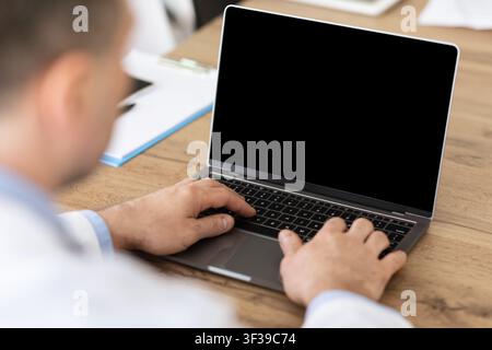 Man working on laptop with empty black screen for mockup Stock Photo