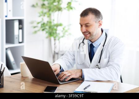 Portrait of mature practitioner using laptop and typing Stock Photo