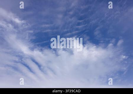 A serene sky filled with delicate, wispy cirrus clouds that stretch and flow across the frame. The soft white clouds against a vibrant blue backdrop c Stock Photo