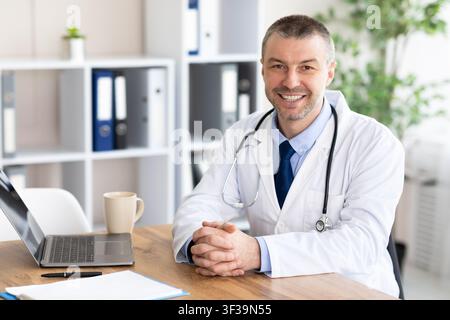 Portrait of cheerful mature doctor posing, smiling at camera Stock Photo