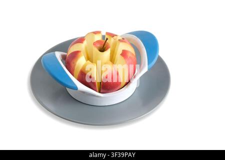 Sliced red apple in plastic slicer device on gray plate isolated on white background Stock Photo
