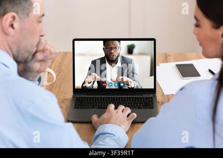 Workers having discussion during video call with colleague Stock Photo