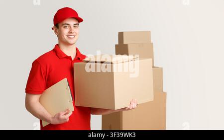 Courier and package in warehouse. Deliveryman holding box and tablet near stack of parcels Stock Photo