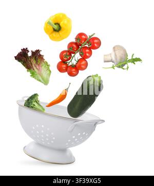 Vegetables and colander flying in air on white background Stock Photo