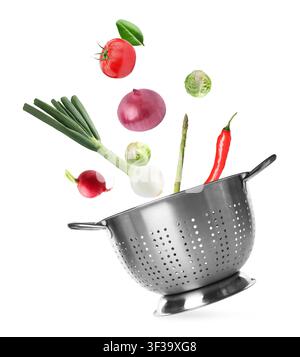Vegetables and colander flying in air on white background Stock Photo