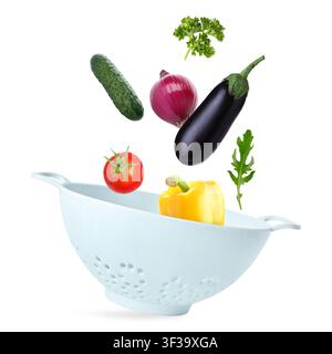 Vegetables and colander flying in air on white background Stock Photo