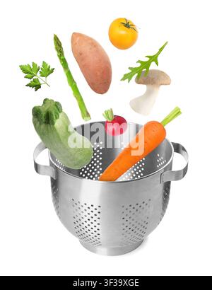 Fresh vegetables falling into colander on white background Stock Photo