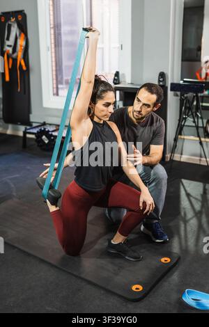 Woman doing functional training with resistance band and coach Stock Photo