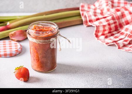 Homemade strawberry rhubarb jam in glass jar with fresh strawberries Stock Photo