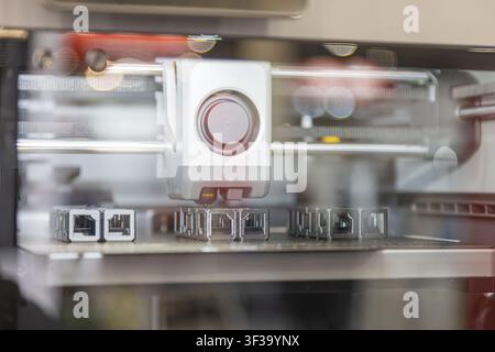 Modern 3D printer precision in action, focused on extruder head depositing material onto build platform, intricate printed objects, clean indoor setti Stock Photo