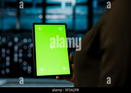 Close up of admin in sustainable data center implementing green technologies using isolated screen tablet. Worker uses mockup device and energy efficient solution to reduce server hub carbon footprint Stock Photo