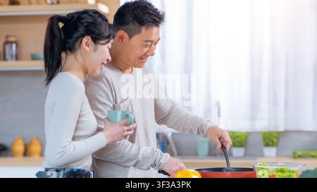 Smiling Asian Couple Cooking Together In Modern Kitchen, Happy Cooking Concept Stock Photo