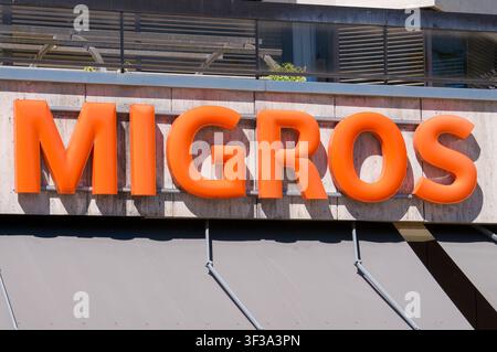Lugano, Ticino, Switzerland - 11th June 2026: Migros supermarket iconic 3D orange logo sign mounted on a store facade. Stock Photo