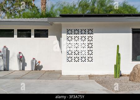 A white mid-century modern house in Palm Springs, California features a geometric breeze block and cacti desert landscaping. Stock Photo