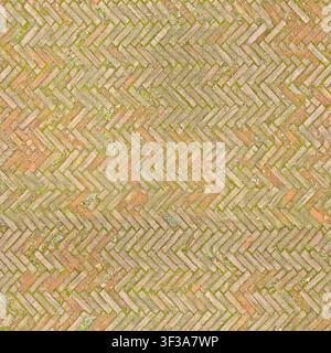 Top view of old red terracotta bricks arranged in a herringbone pattern with subtle moss in joints. Stock Photo