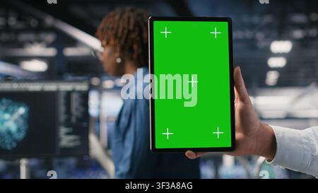 Close up of data center admin using mockup tablet to update storage arrays software, configuring network virtualization. Server room IT expert using chroma key device to verify settings Stock Photo