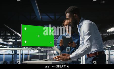 Data center colleagues working on green screen PC, updating storage infrastructure. IT engineering team using mockup computer in server hub workspace filled with networking tech, Stock Photo