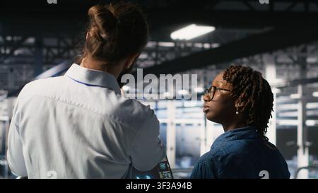 Data center manager overseeing work done by admin using neural network AI LLM visualization. Server farm team leader and worker overseeing rigs powering machine learning processes Stock Photo