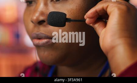 Closeup of employee talking with customer using headphones microphone to identify new sales opportunities. Account manager in office uses audio headset, bonding with client to generate leads, camera A Stock Photo