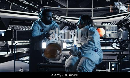 Teamworking cosmonauts chatting, exploring deep space during mankind survival expedition. Astronauts doing human expansion in space mission in spacecraft powered by advanced engineering Stock Photo