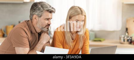 Couple Collaborating On Laptop In Modern Kitchen, Smiling, Engaged In Project Stock Photo