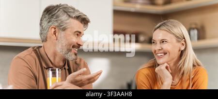 Smiling Caucasian Man And Woman Engaged In Joyful Conversation At Home, Kitchen Setting Stock Photo