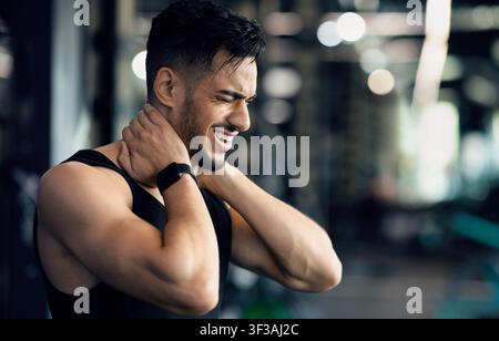 Body Injury. Portrait of young arab man suffering from pain in neck Stock Photo