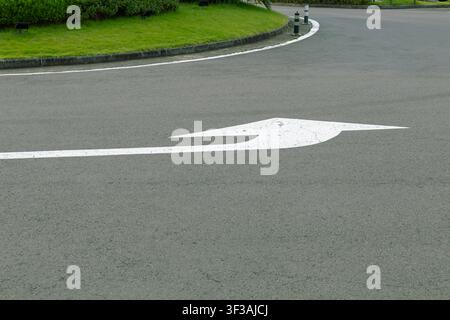 White Left Turn Direction Arrow Painted on Asphalt Road Stock Photo