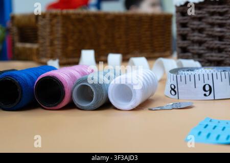 Colorful Sewing Threads Measuring Tape and Needle on Tailor Table Stock Photo