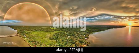 A stunning 180° panorama over Lake Jesup shows a double rainbow near the SR-417 bridge as the setting sun glows and reflects across calm water.default Stock Photo