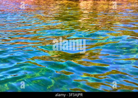 Vivid Sunlit Water Surface with Ripples and Colorful Reflections Stock Photo