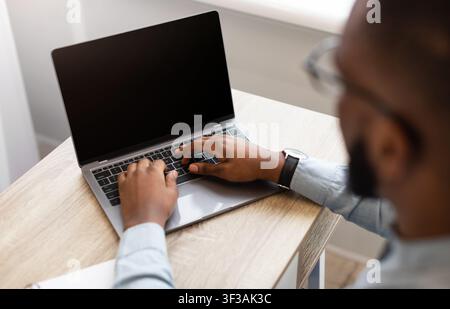 Black Businessman Using Laptop With Empty Screen Indoor, High-Angle View Stock Photo