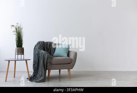 Modern boho cozy corner of home. Gray vintage armchair with blue pillow and blanket Stock Photo