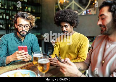 Friends using smartphones and drinking beer at the bar Stock Photo