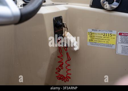 A close-up view of a boat's ignition switch panel showing a red safety lanyard (engine cut-off switch) hanging from the key on the console. Stock Photo
