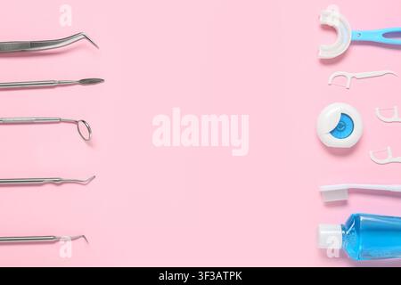 Dental instruments and oral hygiene products arranged on a pink background for dentistry and health care concepts, the left side displays various stai Stock Photo