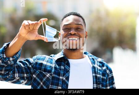 Portrait of happy man taking off mask in the city Stock Photo