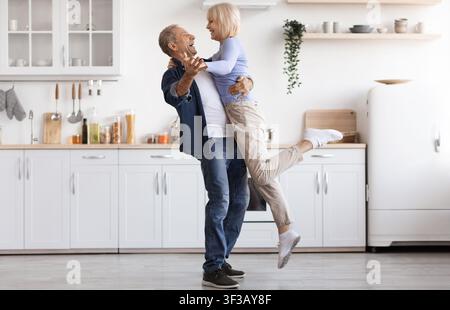 Romantic elderly man and woman dancing at kitchen Stock Photo
