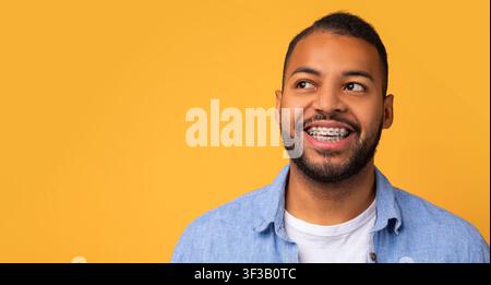 Smiling young african american man with orthodontic braces looking at copy space Stock Photo