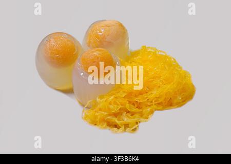 Close-up of duck egg jelly, a unique Thai dessert made from agar molded in egg shells, served with sweetened golden strands of foi thong Stock Photo