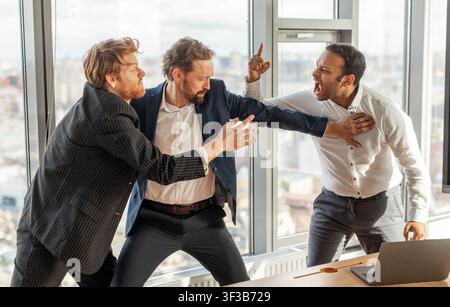 Three Businessmen Involved in Intense Argument in a Modern Office Stock Photo