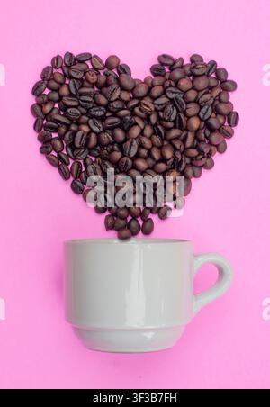 Heart Shape Coffee Beans Rising from White Cup on Pink Background Stock Photo