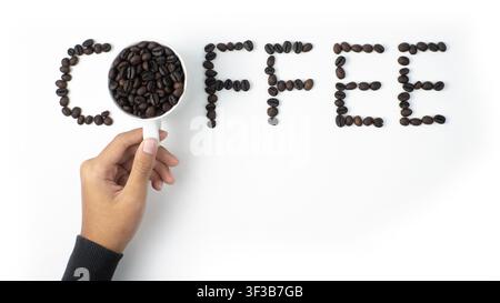 Hand Arranging Coffee Word Made from Roasted Beans on White Background Stock Photo