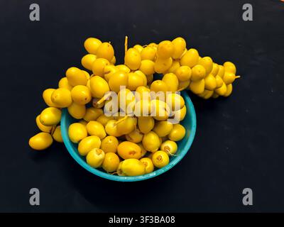fresh healthy Ripe raw Yellow Dates Fruit Cluster Served On bowl Top View Composition Stock Photo