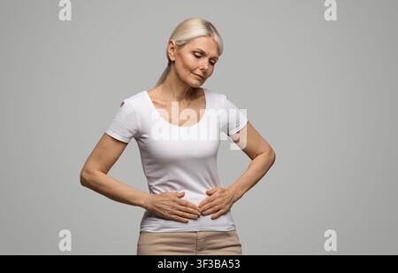 Stomach Pain. Sick mature woman suffering from acute abdominal ache Stock Photo