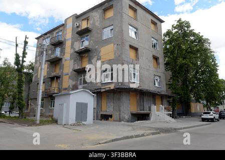 Boarded up windows of an apartment block due to bomb and drone attack damage in Kharkiv, eastern Ukraine, painted with street art. May 2026 Stock Photo