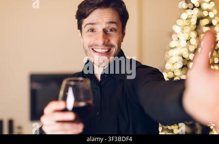 Young man drinking red wine, looking at camera Stock Photo