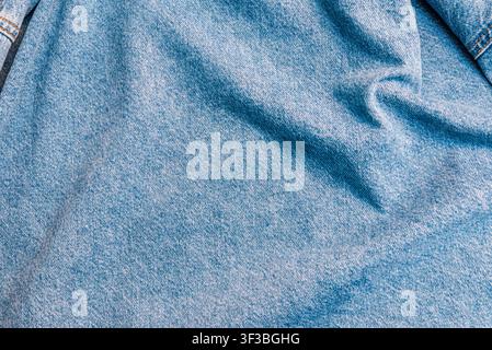 Minimalist wrinkled jeans cloth banner featuring a soft drapery pattern. Casual blue cotton denim surface background with space for text. Stock Photo