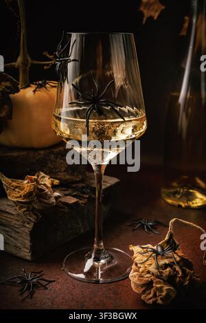Close-up of wine glass with sparkling white wine and spider decorations on Halloween styled table Stock Photo