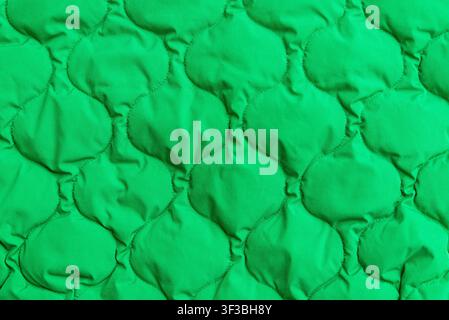 Vibrant green quilted fabric texture background with copy space. Minimalist bright green padded textile banner featuring a decorative curved geometric Stock Photo